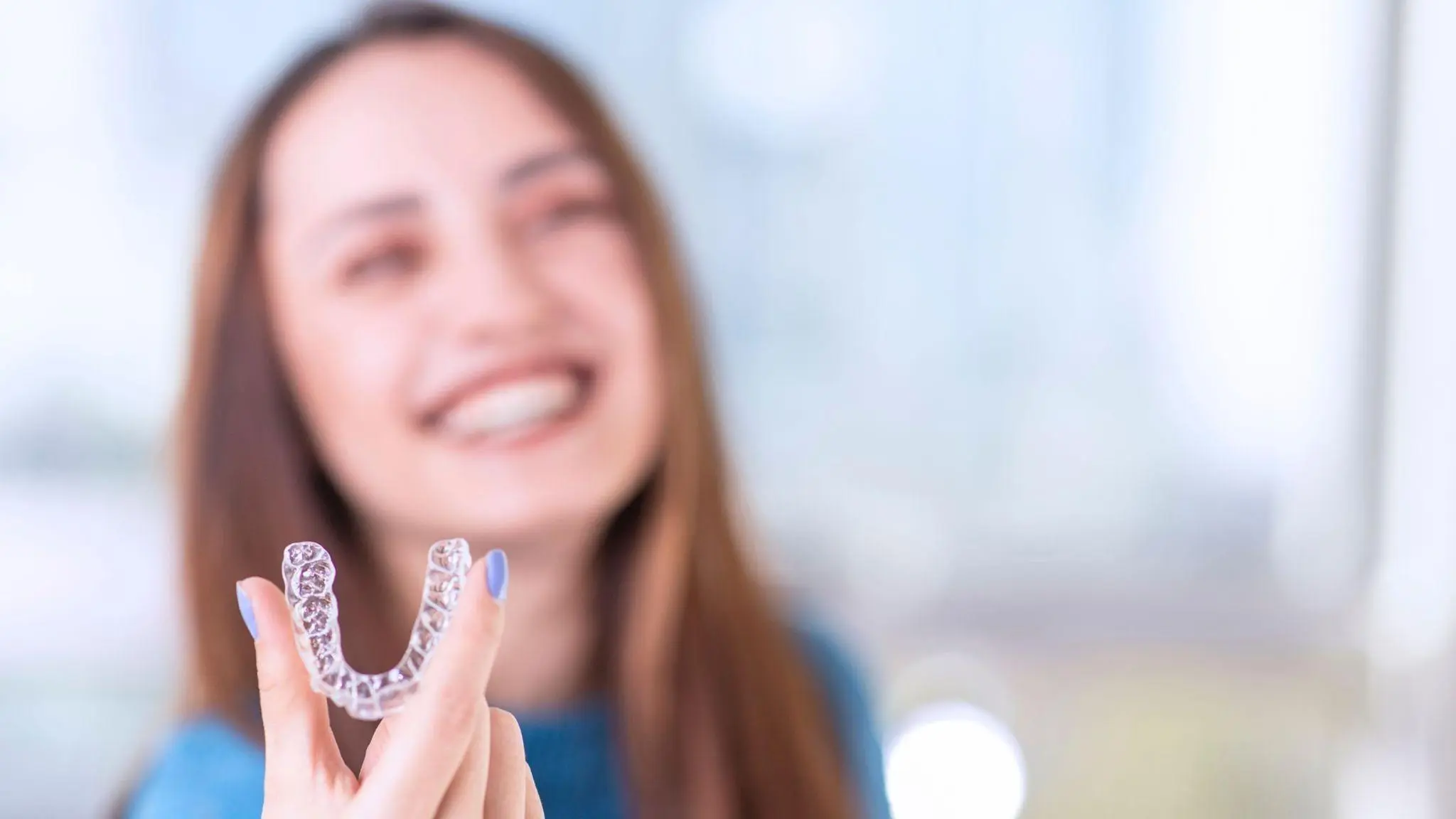 Patient holding a clear Invisalign aligner tray